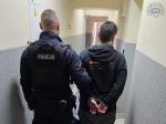 policjant prowadzący zatrzymanego mężczyznę zakutego w kajdanki przez korytarz