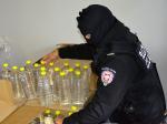 Fotografia przedstawia funkcjonariusza w trakcie czynności związanych z ujawnieniem nielegalnego alkoholu